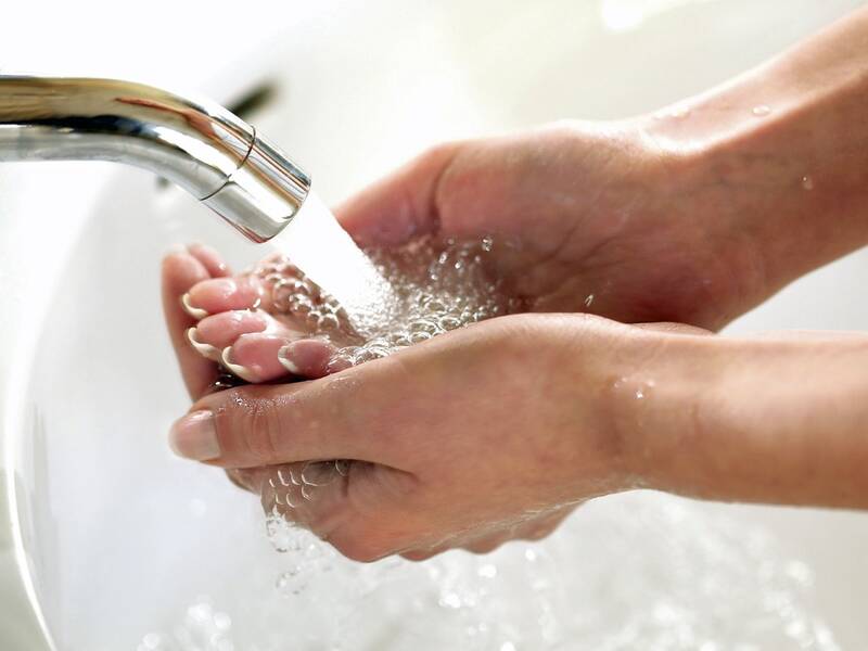 Haltende Hände unter einem Wasserhahn mit laufendem Wasser