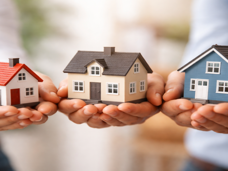 Drei Hände halten jeweils ein kleines Haus in ihren Handflächen 