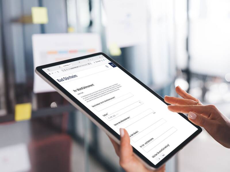 Tablet mit geöffnetem Online-Fragebogen zur Anmeldung in Bad Dürrheim, gehalten von einer Person mit sichtbaren Händen