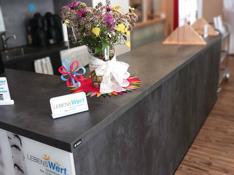 Theke mit Blumengesteck, Windrad und Informationskarten in einem modernen Innenraum mit Holzboden