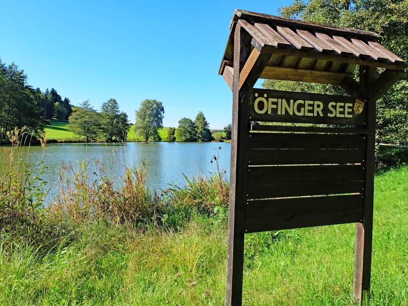 Ein See mit Ufer und Holzschild