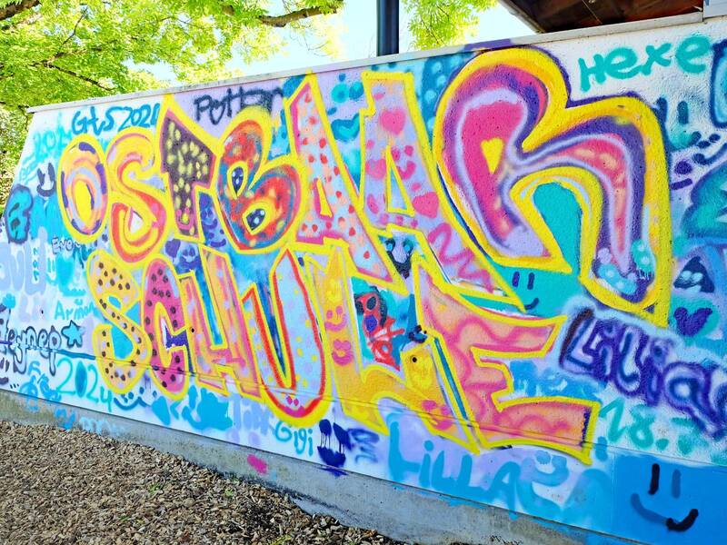 Ein buntes Graffiti an der Schulwand