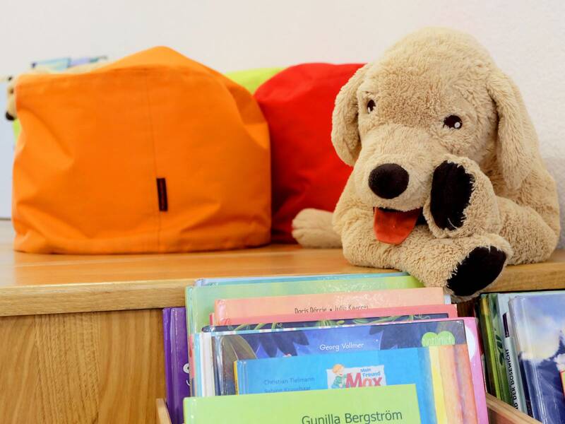Bücherkiste auf der Lesetreppe, bunte Sitzkissen und Kuscheltier