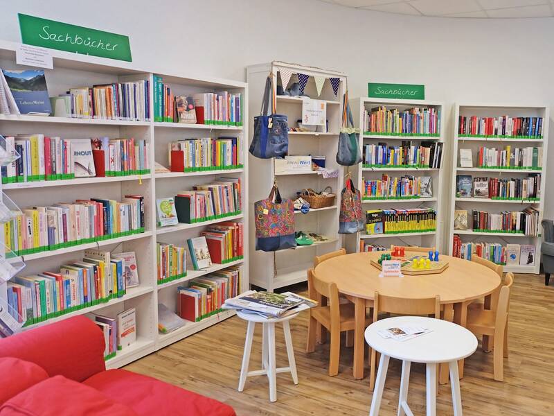 Sitzecke mit Sofa in der Stadtbibliothek. Ein Regal ist mit Selbstgemachtem vom Generationentreff Lebenswert bestückt.