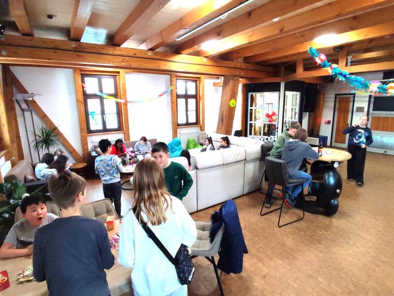 Kinder und Jugendliche in einem Partyraum beim Reden und Spielen