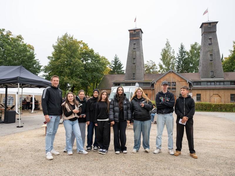 Eine Gruppe von jungen Menschen auf einem Platz vor zwei Türmen mit Flaggen auf den Spitzen