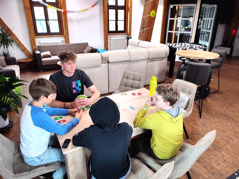 Kinder und Jugendliche spielen Karten an einem Tisch
