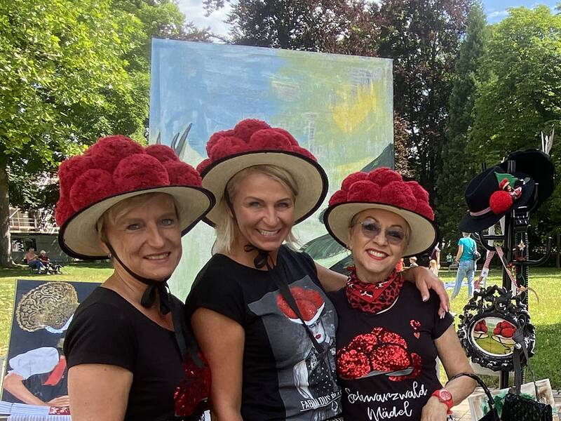Drei Frauen mit rotem Bollenhut.