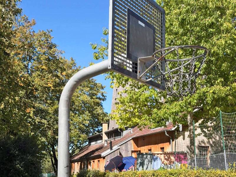 Im Vordergrund ein Basketballkorb. Im Hintergrund der ehemalige Salinenbohrturm sowie Sonenschirme.