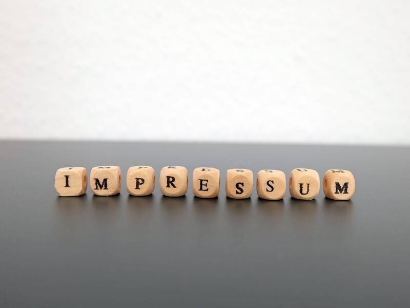 Buchstabenwürfel aus Holz ergeben das Wort Impressum